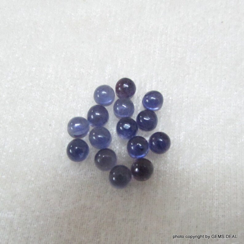May include: A collection of 17 round, smooth, purple gemstones. The gemstones are approximately 5mm in diameter.