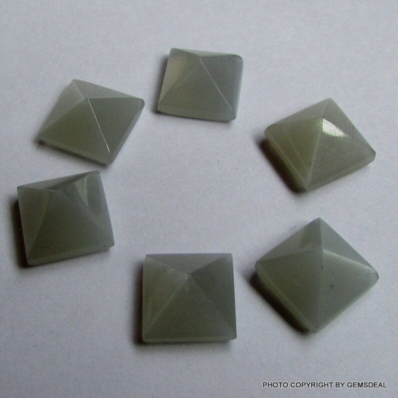 Puede incluir: Seis cabujones de piedra preciosa gris en forma de pir&aacute;mide, cada uno con una base cuadrada.