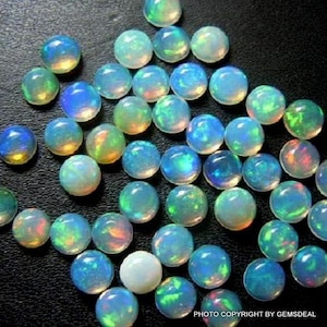 May include: A collection of iridescent opal cabochons in various shades of blue, green, and white. The stones are round and have a smooth, polished finish.
