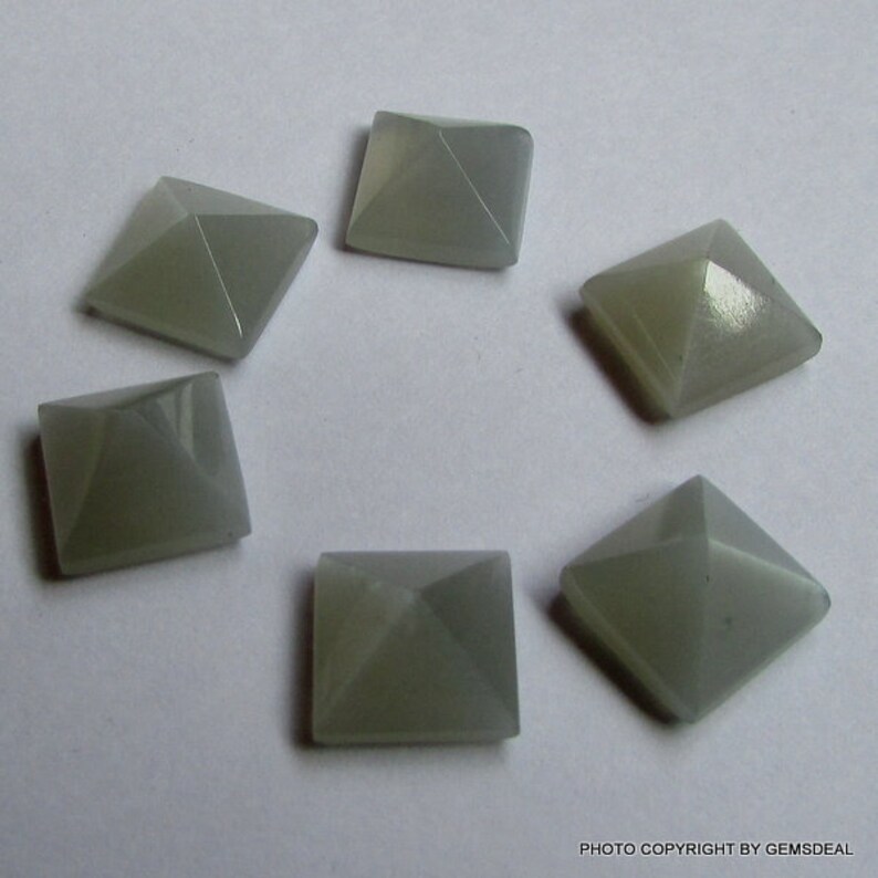 Puede incluir: Seis cabujones de piedra preciosa grises en forma de pir&aacute;mide. Los cabujones est&aacute;n cortados en forma cuadrada con una parte superior puntiaguda.
