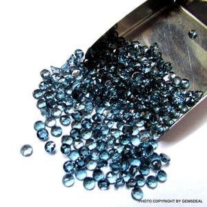 K&ouml;nnte beinhalten: Eine Schaufel gef&uuml;llt mit losen blauen Topas-Edelsteinen. Die Edelsteine sind facettiert und haben verschiedene Gr&ouml;&szlig;en und Formen.