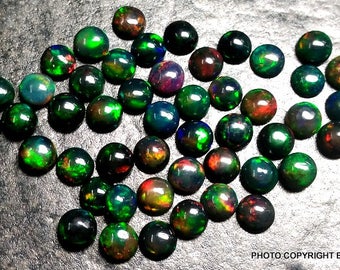 May include: A collection of 40 round, black opal cabochons with green, red, and blue iridescent flashes. The opals are approximately 6mm in diameter.