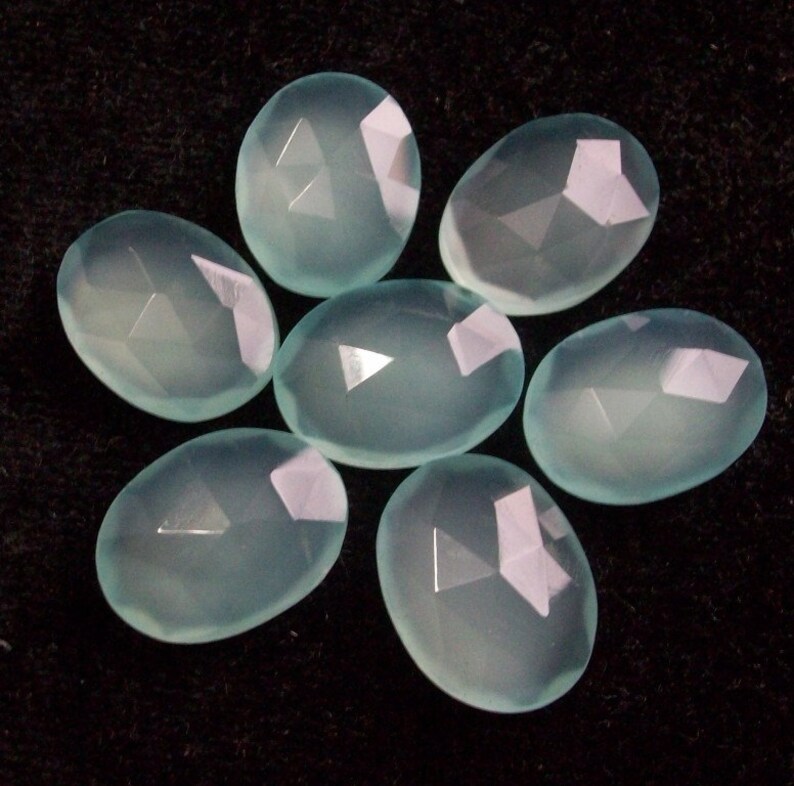 Peut inclure: Sept pierres pr&eacute;cieuses de calc&eacute;doine ovales de couleur bleu clair avec des surfaces facett&eacute;es.