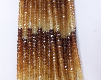 May include: A strand of faceted brown and yellow gemstone beads. The beads are graduated in size, with the larger beads at the top and the smaller beads at the bottom. The beads are strung on a clear thread.