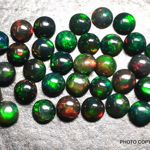 May include: A collection of 30 round, black opal cabochons with green and red flashes. The opals are approximately 6mm in diameter.