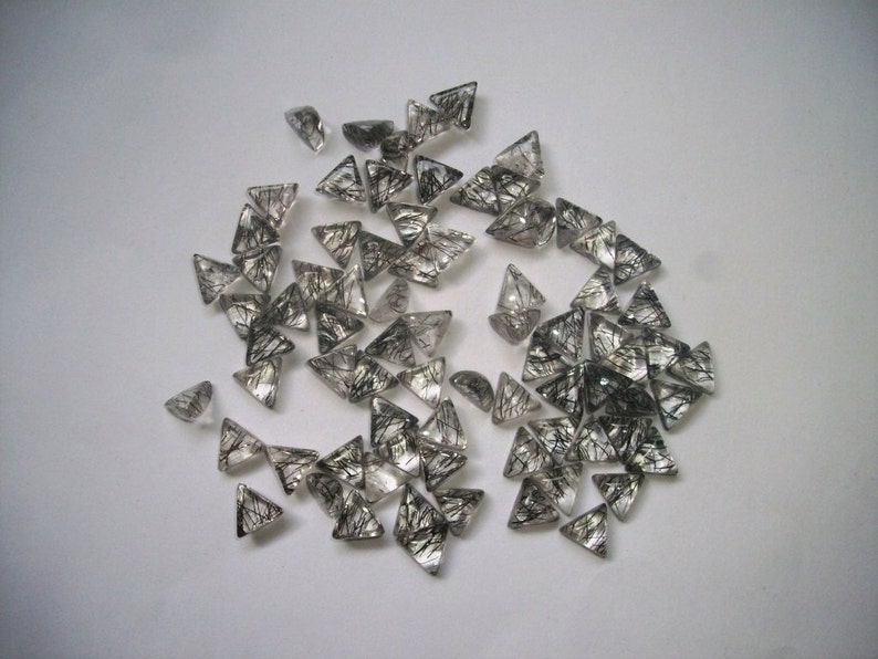 May include: A collection of black tourmaline gemstone points, also known as black quartz, in a triangular shape. The stones are clear with black inclusions.