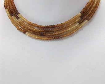May include: A multi-strand necklace made of brown and light brown faceted gemstone beads.