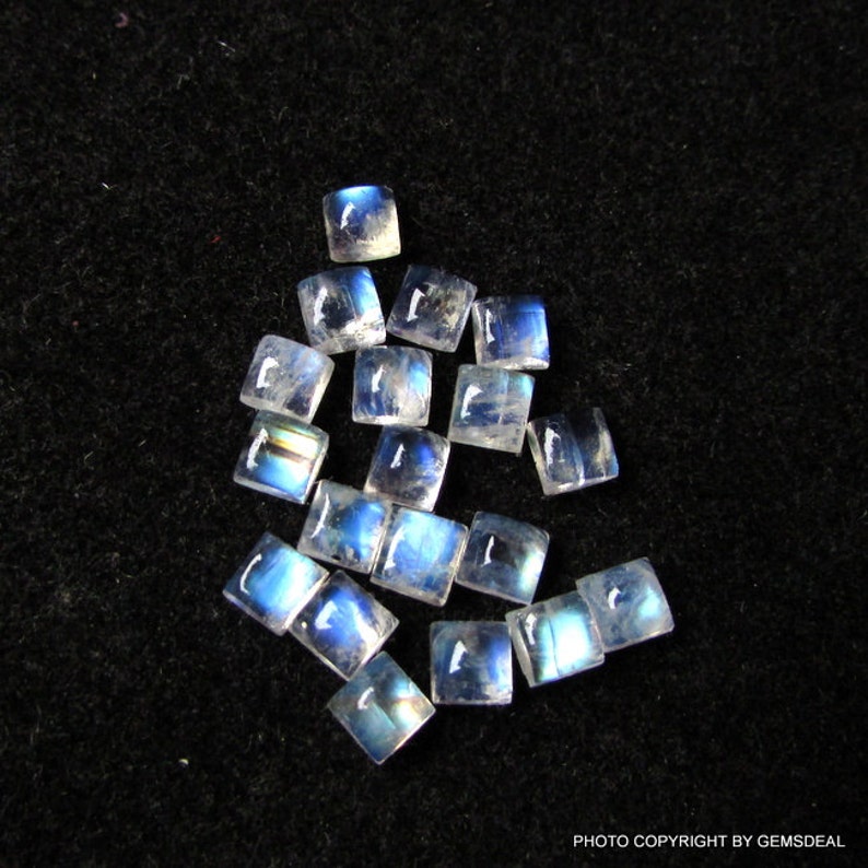 K&ouml;nnte beinhalten: Eine Sammlung von 15 regenbogenfarbenen blauen Mondstein-Quadratcabochons, die jeweils etwa 6 mm x 6 mm messen. Die Steine sind lose und bereit, in Schmuck eingefasst zu werden.