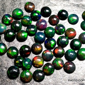 May include: A collection of 40 round, black opal cabochons with green, red, and blue iridescent flashes. The opals are approximately 6mm in diameter.