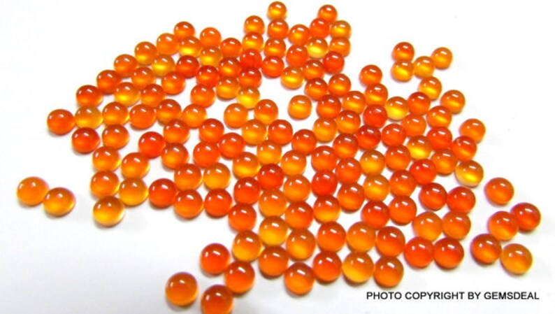 May include: A large group of round, orange carnelian gemstones. The gemstones are smooth and polished, with a slight variation in color.