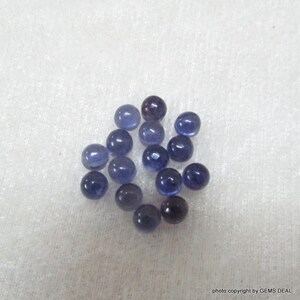 May include: A collection of 18 round, blue gemstone beads. The beads are smooth and have a slight sparkle.
