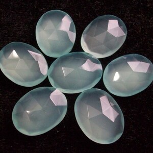 Peut inclure: Sept pierres pr&eacute;cieuses de calc&eacute;doine ovales de couleur bleu clair avec des surfaces facett&eacute;es.