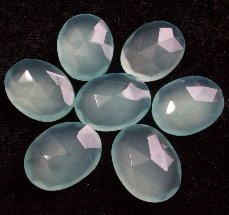 Peut inclure: Sept pierres pr&eacute;cieuses de calc&eacute;doine ovales de couleur bleu clair avec des surfaces facett&eacute;es.