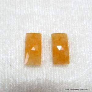 Peut inclure: Deux pierres précieuses rectangulaires orange avec un centre clair et facetté.