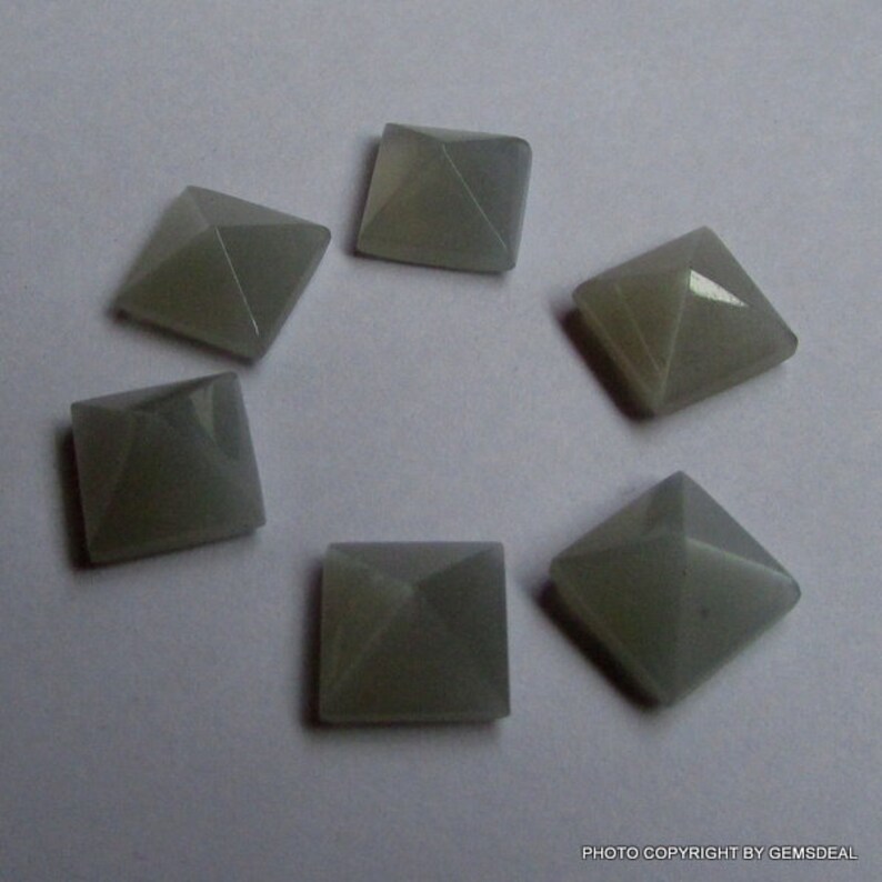 Puede incluir: Seis cabujones de piedra preciosa grises en forma de pir&aacute;mide, cada uno con una base cuadrada.