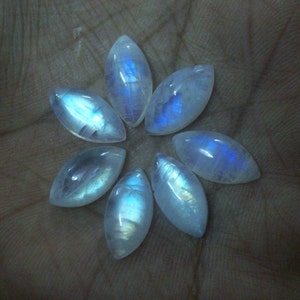 Puede incluir: Siete cabujones de piedra lunar blanca iridiscente en forma de marquesa. Las piedras tienen un brillo azul.