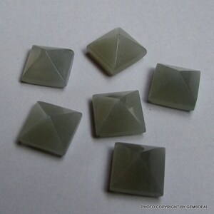 Puede incluir: Seis cabujones de piedra preciosa gris en forma de pir&aacute;mide, cada uno con una base cuadrada.
