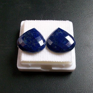 Könnte beinhalten: Zwei tropfenförmige Lapislazuli-Edelsteine mit goldenen Flocken, in einer weißen Schaumstoff-Präsentationsbox.