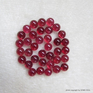 Puede incluir: Una colección de 25 cabujones redondos de rubí rojo. Los cabujones son lisos y pulidos, con un acabado brillante.