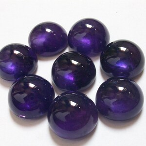 May include: Eight round, purple amethyst cabochons, each with a smooth, polished surface.