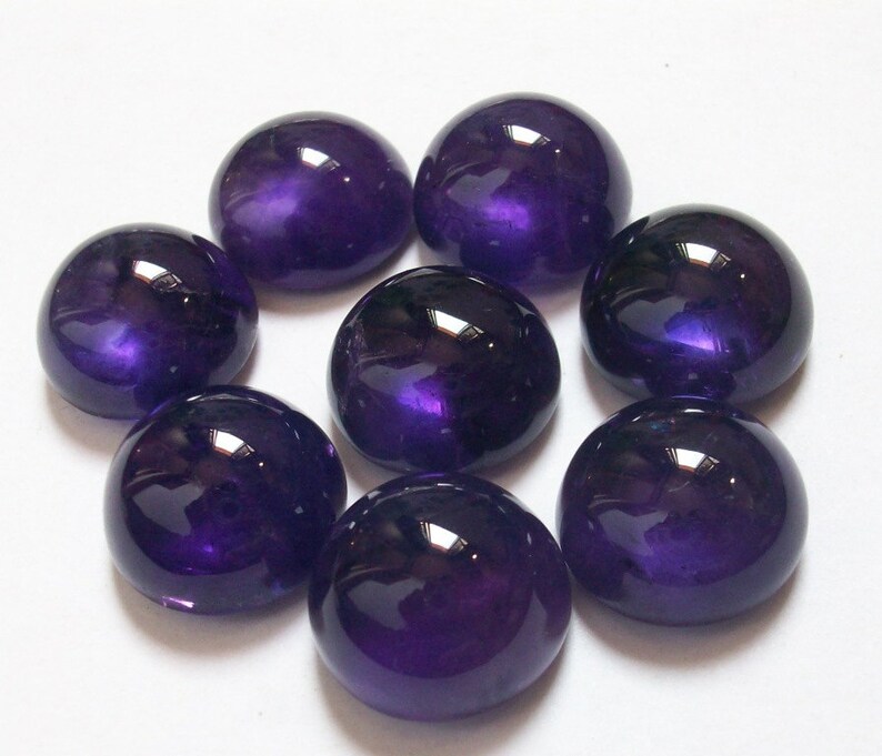 May include: Eight round, purple amethyst cabochons, each with a smooth, polished surface.