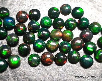 May include: A collection of 30 round, black opal cabochons with green and red flashes. The opals are approximately 6mm in diameter.