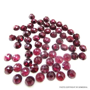 Peut inclure: Une collection de 50 pierres précieuses de grenat rouge facettées et non montées. Les pierres sont rondes et ont une finition polie.