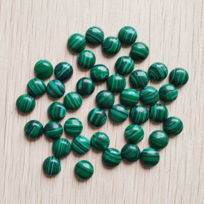 Pu&ograve; includere: Una collezione di cabochon di malachite verde, ognuno con un motivo unico di linee verdi e nere vorticose. I cabochon sono lisci e lucidi, e sono perfetti per la creazione di gioielli o altri progetti artigianali.