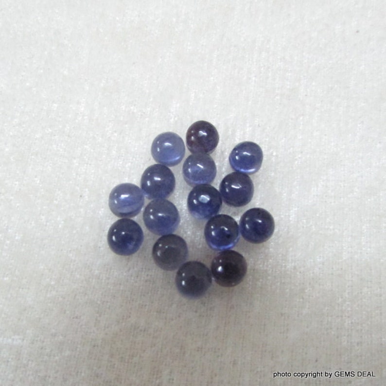 May include: A collection of 16 round, smooth, purple-blue gemstone beads. The beads are approximately 5mm in diameter and have a polished finish.