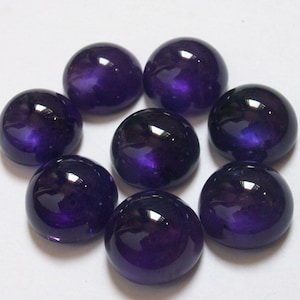 May include: Eight round, purple cabochon gemstones. The gemstones are smooth and shiny.