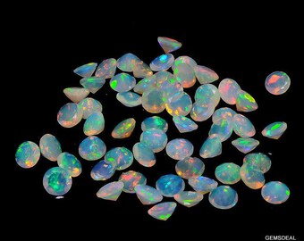 May include: A collection of loose, iridescent opal gemstones in various sizes and shapes. The opals are a pale white color with flashes of green, blue, and orange.
