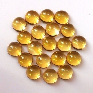 May include: A collection of 18 round, translucent, yellow-gold gemstones. The gemstones are smooth and polished, with a slight variation in size and shape.