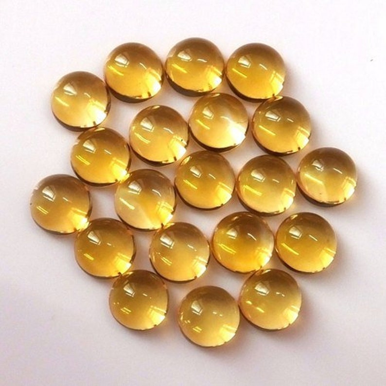 May include: A collection of 18 round, translucent, yellow-gold gemstones. The gemstones are smooth and polished, with a slight variation in size and shape.