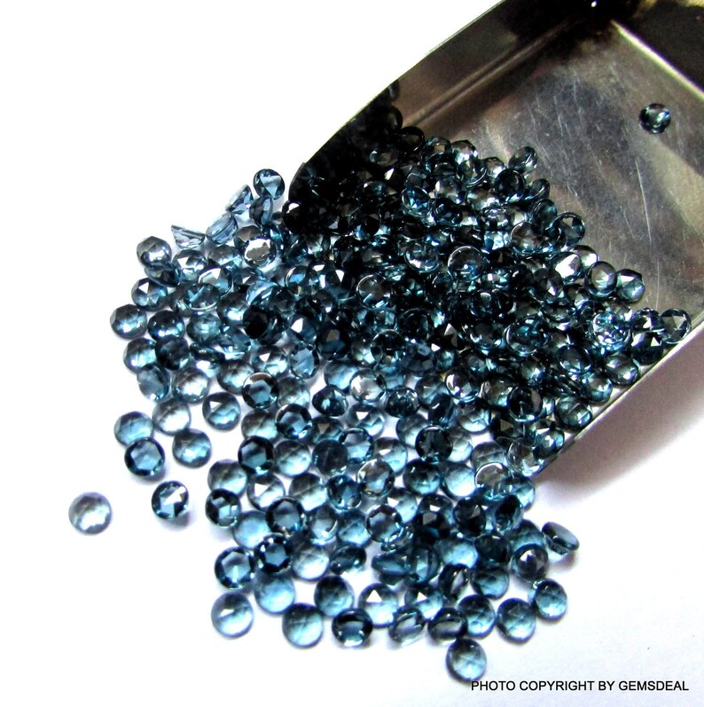 K&ouml;nnte beinhalten: Eine Schaufel gef&uuml;llt mit losen blauen Topas-Edelsteinen. Die Edelsteine sind facettiert und haben verschiedene Gr&ouml;&szlig;en. Die Schaufel ist aus Metall und silberfarben.