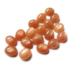 May include: A collection of 17 oval-shaped, orange sunstone cabochons. The stones have a smooth, polished surface and a subtle shimmer.