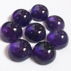 May include: Eight round, purple amethyst cabochons, each with a smooth, polished surface and a slight sheen.