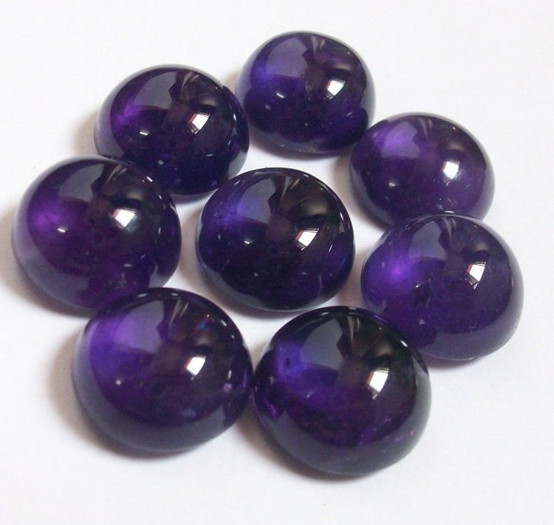 May include: Eight round, purple amethyst cabochons, each with a smooth, polished surface and a slight sheen.
