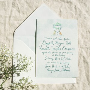 May include: A wedding invitation with a watercolour design featuring a couple of dogs and a crest with the initials "M+K". The text reads "Together with their families, Elizabeth Morgan Nall and Kenneth Douglas Edenfield III request the pleasure of your company at their wedding, Saturday, April 30, 2016, six o'clock in the evening, Heron Pointe at the Villas, Orange Beach, Alabama."
