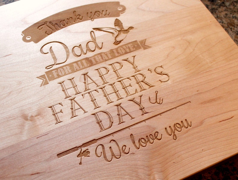 May include: A wooden cutting board with an engraved message that reads "Thank you Dad - For all that love - Happy Father's Day - We love you". The message is surrounded by a decorative border and includes a small image of a bird.