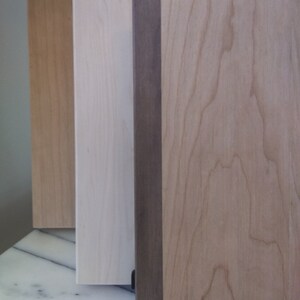 May include: Three wood panels, one with a dark brown stain, one with a light brown stain, and one with a natural wood finish.