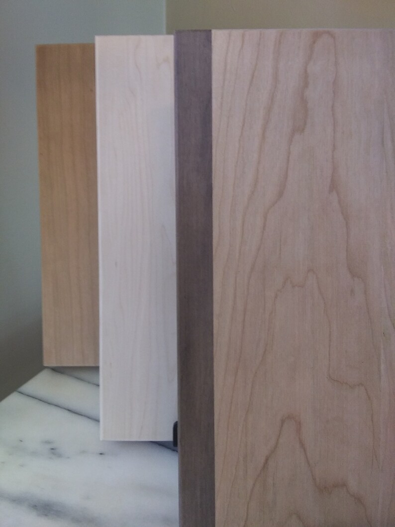 May include: Three wood panels, one with a dark brown stain, one with a light brown stain, and one with a natural wood finish.