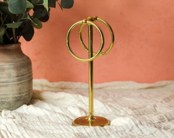 May include: Gold metal stand with three circular rings for holding jewelry or other small items.