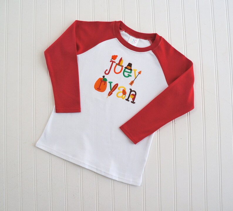 Puede incluir: Camiseta de b&eacute;isbol de manga larga blanca con mangas rojas. La camiseta tiene un dise&ntilde;o de tem&aacute;tica de Acci&oacute;n de Gracias con el nombre "Joey Ryan" escrito en letras de colores y decorado con iconos de tem&aacute;tica oto&ntilde;al.
