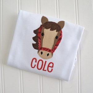 May include: White t-shirt with a brown and red horse applique and the name "COLE" embroidered in red.