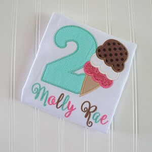 May include: A white t-shirt with a turquoise number two, a brown and pink ice cream cone, and the name "Molly Rae" embroidered in brown and pink.