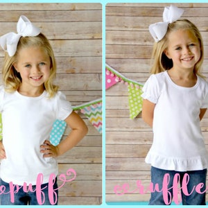 May include: Two photos of a young girl wearing a white t-shirt with a ruffle at the bottom. The girl on the left is wearing a white bow in her hair and the girl on the right is wearing a white bow with a ruffle. Both girls are standing in front of a wooden background with a colorful garland.