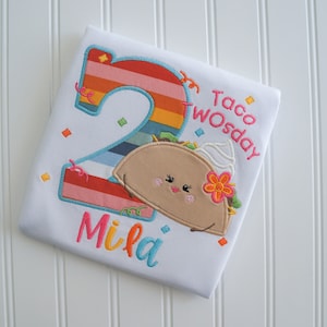 May include: White toddler shirt with a colorful number two, a cartoon taco with a smiling face, and the text "Taco Twosday" and "Mila".