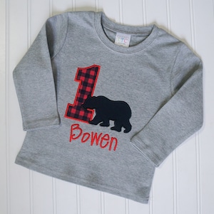 May include: Gray long-sleeve shirt with a red and black plaid number one and a black bear silhouette. The shirt is personalized with the name "Bowen".