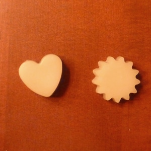 May include: Two small, off-white, wax melts, one shaped like a heart and the other shaped like a sun.