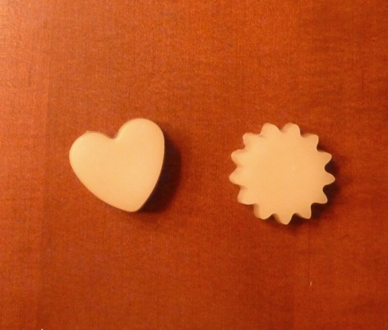 May include: Two small, off-white, wax melts, one shaped like a heart and the other shaped like a sun.